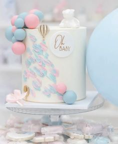 a baby shower cake is decorated with balloons and pastel blue, pink, and white icing