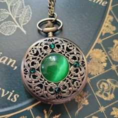 "This unique old fashioned styled pocket watch features a green cabochon at the center surrounded by emerald colored Swarovski crystals.  The clock face is revealed by pushing a button at the top.   There is also a mechanism, located at the top, that you can use to adjust the time.    A battery IS included in the watch so there is no need to purchase one separately.   The pocket watch measures  2-1/2\" tall and 2\" wide and it will come on a bronze chain in the length of your choice. Tip: If you Fancy Pocket Watch, Fantasy Watch, Pocket Clock, Pocket Watch Art, Steampunk Pocket Watch, Old Pocket Watches, Antique Pocket Watch, Steampunk Watch, Pocket Watch Necklace