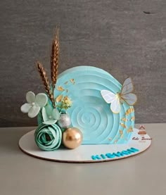 there is a blue cake with gold decorations on the plate and flowers next to it