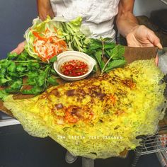 a person holding a large pizza with toppings on it