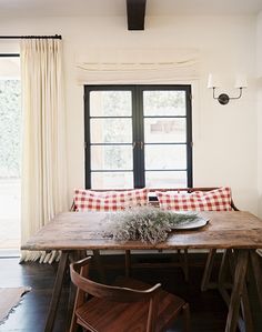 a dining room table with two chairs and a bench in front of the window that overlooks an outdoor patio