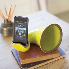 a yellow cup sitting on top of a wooden table next to a cell phone and books