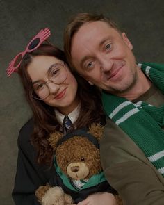 a man and woman posing for a photo with teddy bears on their lap, both wearing glasses