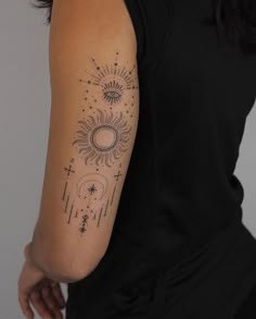 a woman's arm with an intricate sun and stars tattoo on the left arm