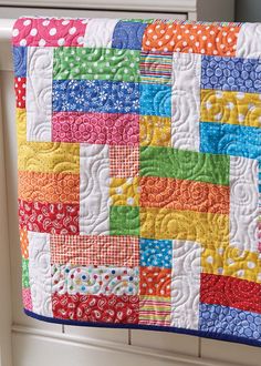 a colorful quilt hanging from the side of a window sill with polka dots on it