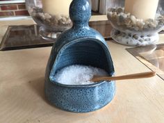 a blue ceramic salt and pepper shaker sitting on a table next to two candles