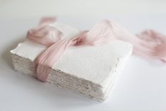 two pieces of paper with pink and white yarn on them sitting on top of each other