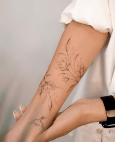 a woman's arm with a flower tattoo on her left forearm and right leg