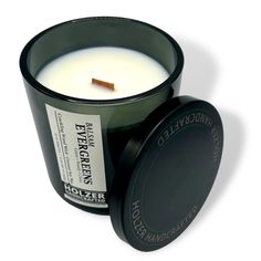 an image of a candle that is in a black container with the lid open to show it's contents