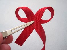 a person holding a pair of scissors with a red ribbon on it