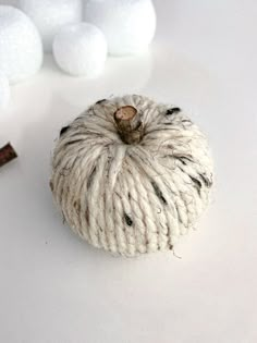 a ball of yarn sitting next to some cotton balls on a white surface with cinnamon sticks in the background