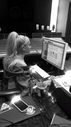 a woman sitting at a desk in front of a computer and sound mixing equipment with pink arrows above her head