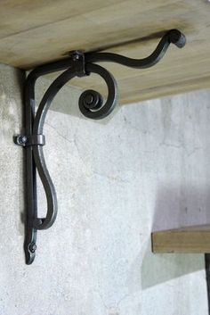 an iron shelf bracket on the side of a white stucco wall with wood planks