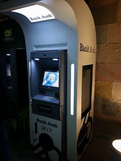 an atm machine sitting in front of a wall next to a lamp and some lights