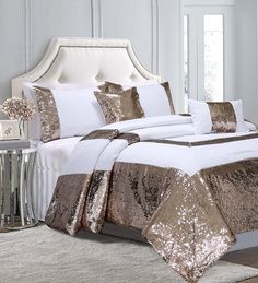 a white bed with gold sequins and pillows on top of it in a room