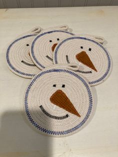 four woven coasters with an image of a snowman on one side and a bird on the other