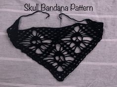 a black crocheted triangle on top of a white sheet with the words skull bandana pattern