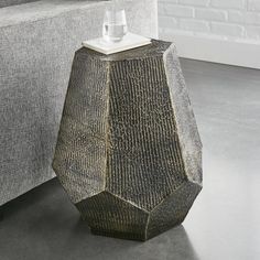 a vase sitting on top of a table next to a gray couch in a living room