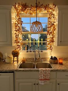 a kitchen sink under a window decorated with fall leaves