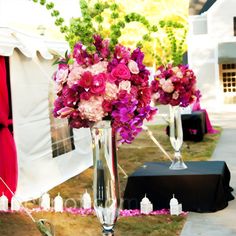 a vase filled with pink and purple flowers sitting on top of a grass covered field