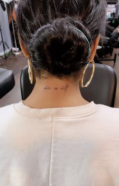 the back of a woman's head with tattoos on her neck and behind her ear