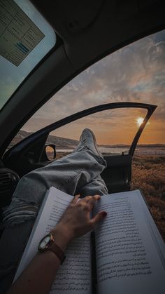 someone is reading a book while sitting in the back of a car with their hand on an open book