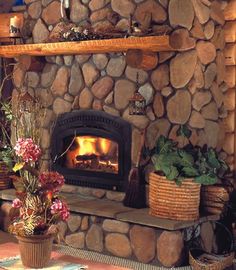 a stone fireplace with potted plants and baskets on the mantle in front of it