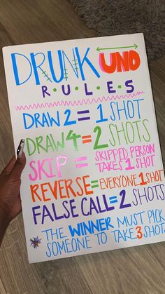 a hand holding up a sign with words written on it that say drunk rules and draw 2 shots