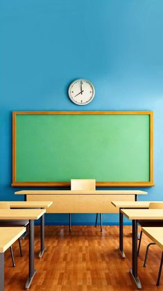 an empty classroom with desks and a clock above the chalkboard on the wall