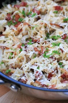 a pan filled with pasta and meat covered in parmesan cheese on top of a wooden table