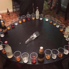 there are many glasses and bottles on the table with drinks in them, all arranged in a circle