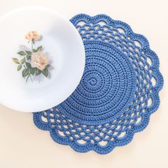 two crocheted placemats and a white plate with a flower on it