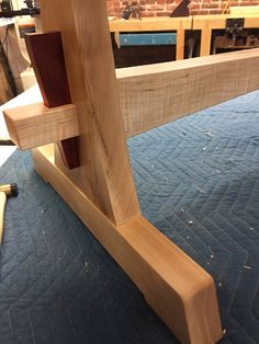 an unfinished piece of wood sitting on top of a blue table cloth covered floor next to a brick wall