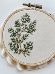 a close up of a embroidery on a piece of cloth with an embroidered plant in the middle