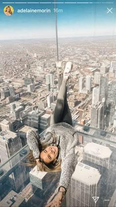 a woman hanging upside down from the top of a skyscraper