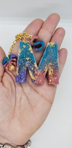 the letter m is made out of polymer and has been placed in someone's hand