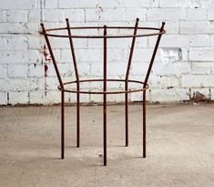 a metal chair sitting on top of a cement floor next to a white brick wall