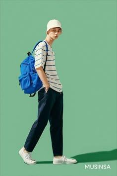 a young man with a blue backpack and white shoes walking across a green background,