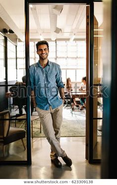 a man standing in an open doorway with his hands in his pockets and smiling at the camera