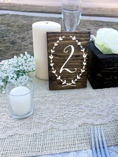 the table is set with candles, flowers and two wooden blocks that spell out the numbers