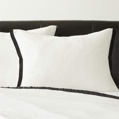 two white and black pillows sitting on top of a bed