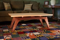 a coffee table sitting on top of a colorful rug in front of a brown couch