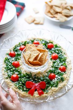 hummus appetizer wreath on a plate with crackers and tomatoes in it