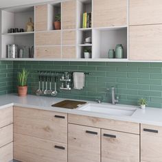 a kitchen with wooden cabinets and green tile backsplash, white countertops and drawers