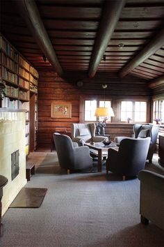 a living room filled with furniture next to a fire place and bookshelf on the wall