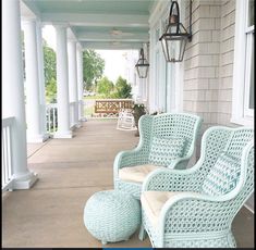 two wicker chairs sitting on the front porch next to an ottoman and lamp fixture