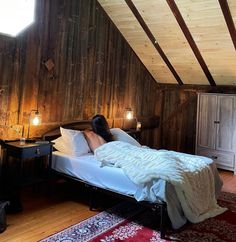 a bedroom with wood paneling and white bedding in the middle of an attic