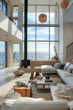 a living room filled with lots of white furniture and large windows overlooking the ocean on a sunny day