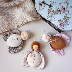 three little dolls are sitting on the table next to a purse and some fabric material