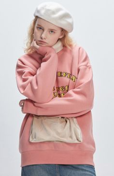 a young woman wearing a pink sweatshirt and white hat with her hands on her face